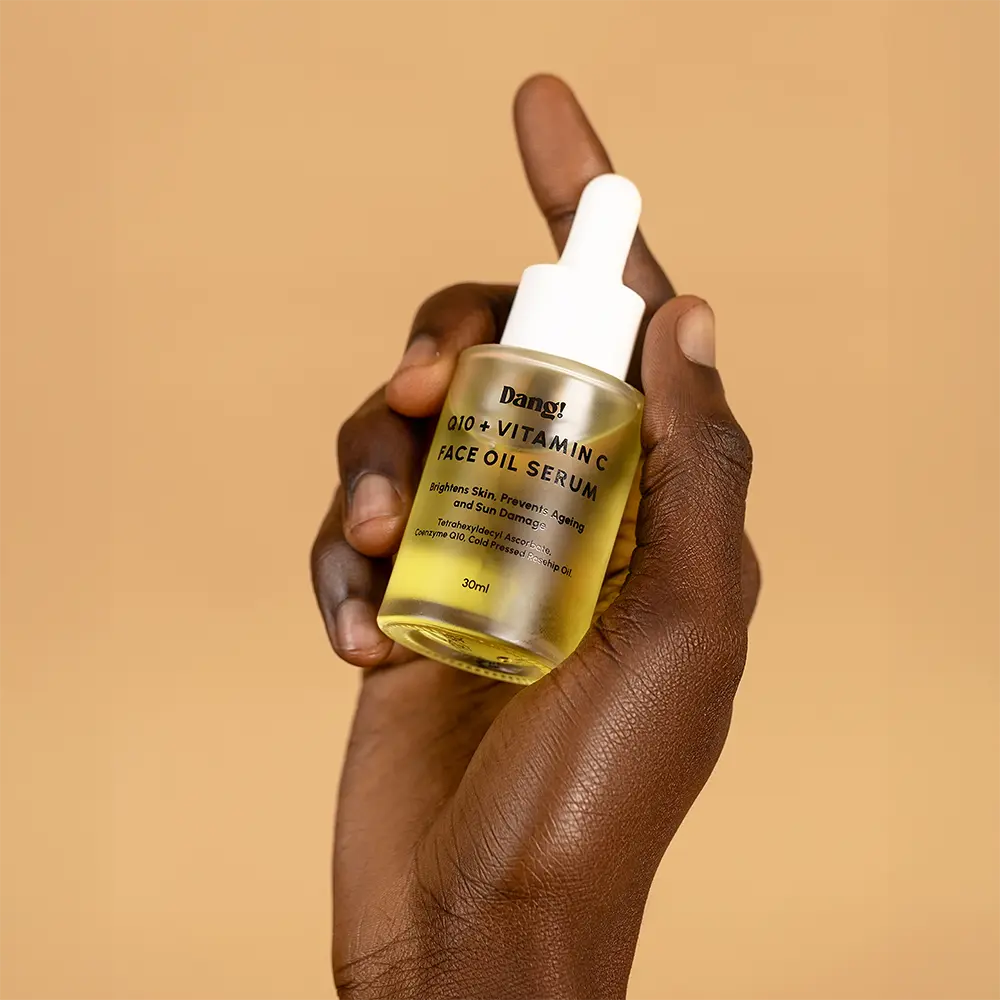 A dark skinned model's hand holding Q10 serum